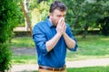 Pollen allergy in springtime concept. Man sneezing in a tissue Royalty Free Stock Photo