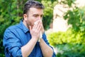 Pollen allergy in springtime concept. Man sneezing in a tissue Royalty Free Stock Photo