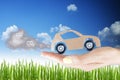 Pollution concept, cardboard car with exhaust gases in woman hand against green grass field Royalty Free Stock Photo