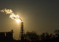 Factory chimney emits or discharges heavy smokes during sunset creating pollution.