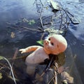 Pollution in public water by a discard,plastic toy doll