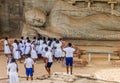 POLONNARUWA, SRI LANKA - JULY 22, 2016: Children in school uniforms visit reclining Buddha statue at Gal Vihara rock Royalty Free Stock Photo