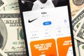 Nike fashion shopping app logo on mobile phone screen. Business background with dollar money banknotes photo