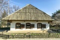 Old traditional village house in the background of the garden. Clay white walls and plank roof