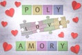 Polyamory word made with wooden colored puzzle pieces and red paper hearts on a table Royalty Free Stock Photo