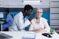 Polyclinic otologist consulting senior patient using otoscope to check ear illness. Royalty Free Stock Photo