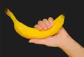 Polygonal hand holds yellow banana black up