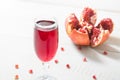 Pomegranate beverage in wineglass over wnite wooden table