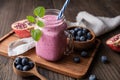 Pomegranate and blueberry smoothie mixed with yogurt and almond milk, served in a glass jar