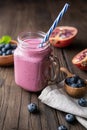 Pomegranate and blueberry smoothie mixed with yogurt and almond milk, served in a glass jar