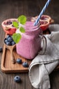 Pomegranate and blueberry smoothie mixed with yogurt and almond milk, served in a glass jar