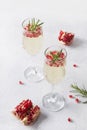 Pomegranate Christmas cocktail with rosemary, sparkling wine on white table. Xmas Holiday drink