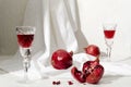 Pomegranate drink, whole and peeled pomegranates, old fashioned glasses white fabric on the bright desk