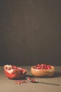 Pomegranate fruit and grains in a wooden bowl and a spoon/Pomegranate fruit and grains in a wooden bowl and a spoon against a dark