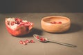 Pomegranate fruit and grains in a wooden bowl and a spoon/Pomegranate fruit and grains in a wooden bowl and a spoon against a dark