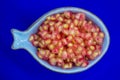 Pomegranate grains ready for healthy finger food served in a heavenly bowl on a blue background Royalty Free Stock Photo