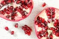 Pomegranate halves, gem like fruits scattered on white board, photo from above