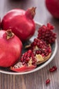 Pomegranate juice in a glass with fresh pomegranates around with scattered seeds on wooden background