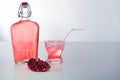 Pomegranate Juice in a glass with ice and Straw and a full bottle.