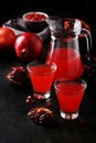 Pomegranate juice in glass and pitcher on the black background Royalty Free Stock Photo