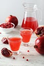 Pomegranate juice in glass and pitcher on the white wooden background Royalty Free Stock Photo