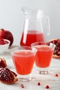Pomegranate juice in glass and pitcher on a white wooden background Royalty Free Stock Photo