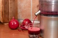 Pomegranate juice pours from a juicer into a glass. Making juice at home