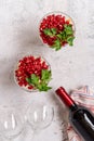 Pomegranate salad decorated with parsley and bottle of red wine with glasses top view flat lay