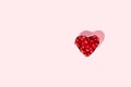 Pomegranate seeds in heart shaped bowl on pink background. Minimal red fruit concept