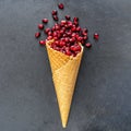 Pomegranate seeds in waffle cone on dark background