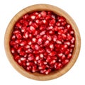 Pomegranate seeds in wooden bowl isolated on white