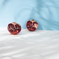 Pomegranate sliced on pastel blue and bright background. Summer shadow and fashion fruit style. Tropical minimal concept