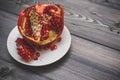 Pomegranate burst ripeness on a white plate on a light wooden ta