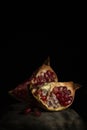 Pomegranate still life - two quarter of a pomegranate and grains on a black background Royalty Free Stock Photo