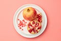 Pomegranates on a grey tray on pastel pink background