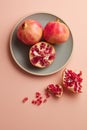 Pomegranates on a grey tray on pastel pink background