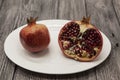 Pomegranates have broken into pieces with red berries on a porcelain plate on a dark background.