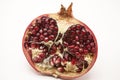 Pomegranates have broken into pieces with red berries on a porcelain plate on a white background.