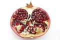 Pomegranates have broken into pieces with red berries on a porcelain plate on a white background.