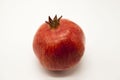 Pomegranates have broken into pieces with red berries on a porcelain plate on a white background.