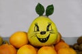 The Pomelo fruit, or pompelmus Latin Citrus maxima is yellow in a grid with a painted muzzle on a background of oranges and bana Royalty Free Stock Photo