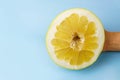 Pomelo half in hand on a blue background close-up