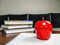 Pomodoro study technique with apple shaped kitchen timer standing on a white empty notebook and books stacked in the background on Royalty Free Stock Photo