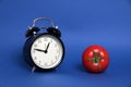 Pomodoro Technique concept - tomato and alarm clock  on blue background Royalty Free Stock Photo