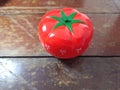 Pomodoro timer in form of a red tomato laying on a wooden table