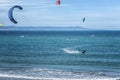 Kitesurfers surfing the wind on waves on a bright sunny summer day