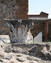 Pompeii ruins in Italy with top of decorative pillar at temple.