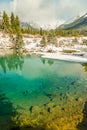 Turquoise and yellow pond with snow covered landscape