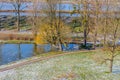 Pond with its frozen waters, a path, bare trees and snow covered grass