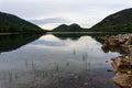 Pond with reeds and rocks and forested hills in the background Royalty Free Stock Photo